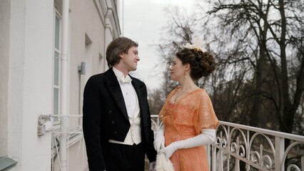 Elegant historical couple holding hands on a balcony
