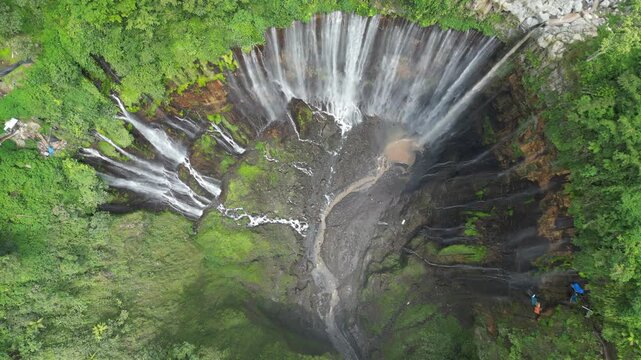 Majestic Tumpak Sewu Waterfall in Indonesia. Powerful water cascades in the tropical Java jungle, drone aerial view. Perfect for travel, nature background, and tourism editorial. Epic landscape.