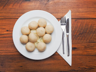 Serving or round traditional Polish dumplings on a white plate and wooden table. Tasty simple food....