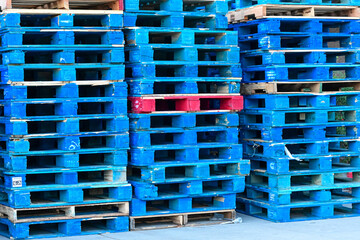Stacks of empty blue plastic pallets arranged in a storage area, representing warehouse logistics, material handling, and supply chain staging operations