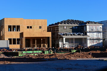 Residential structures at various construction stages with lot preparation for a concrete slab, representing housing development, site grading, and building foundation operations