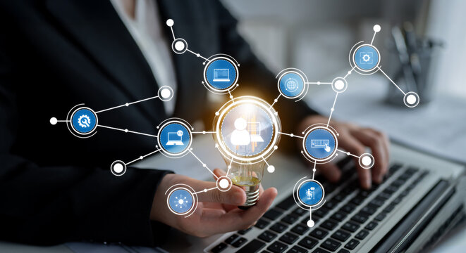 A business professional engages with digital technology icons while working on a laptop in a modern office. The image symbolizes innovation and connectivity in the workplace. Crux - Powered by Adobe