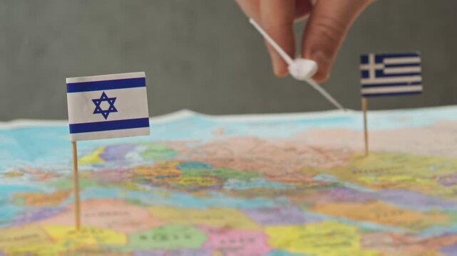 Toy airplane flying from Greece to Israel across detailed world map, symbolizing tourism, vacation trip, European air route and international flight connection between countries.