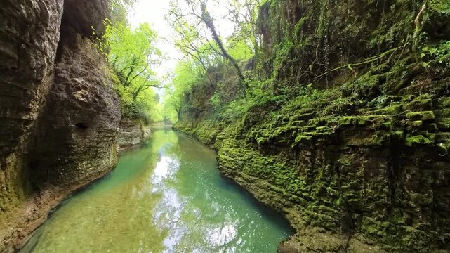 Martvili Canyon in Georgia features stunning rock formations covered in vibrant green moss, creating a picturesque scene along the Abasha River, with clear water flowing through the canyon