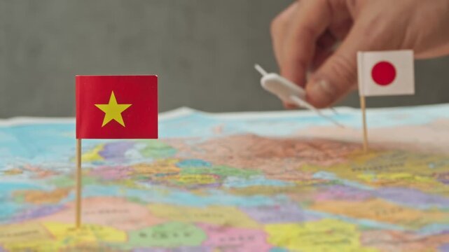Toy airplane between Japan and Vietnam flags over colorful world map, symbol presence of Japanese carriers, code share agreements and development of Vietnam international flight market.