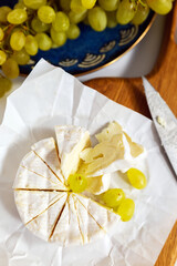 Cheese and grapes on a wooden table with a knife