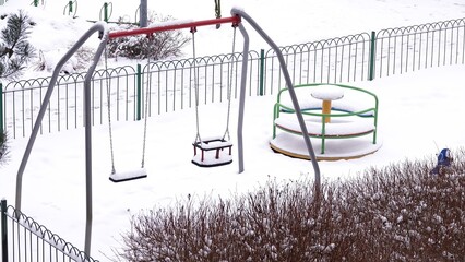 Plac zabaw z huśtawkami i karuzelą pokryty śniegiem © tomo81