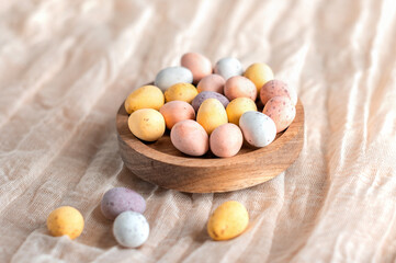 Easter mini eggs, chocolate candy in wooden bowl.