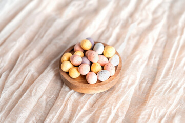 Easter mini eggs, chocolate candy in wooden bowl.