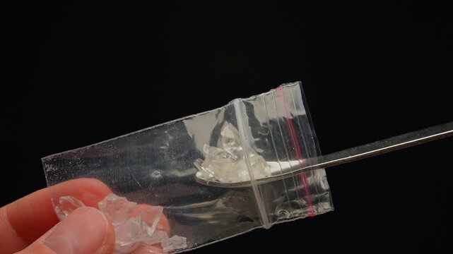 Drug user taking crystal drug from a plastic zip bag concept. Preparation for consumption of Fentanyl, Cocaine, Crystal meth or Crack Cocaine.