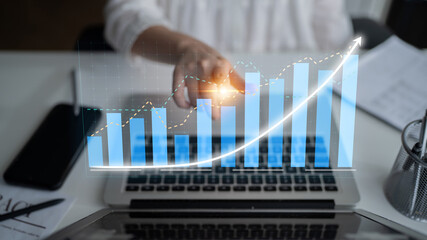 A close-up view of a person interacting with a digital graph on a laptop, illustrating business...
