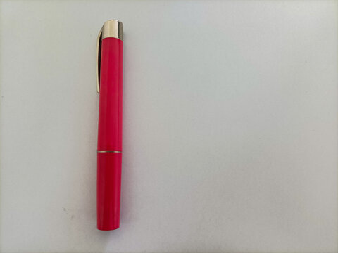 Red medical penlight isolated on a white background, commonly used by doctors and nurses for pupil examination, clinical checks, and healthcare diagnostics.