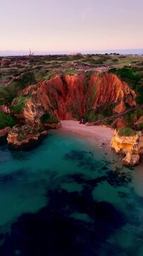 Revealing aerial shot of Praia do Camilo Beach at Golden hour in Lagos, Algarve, Portugal. Vertical video