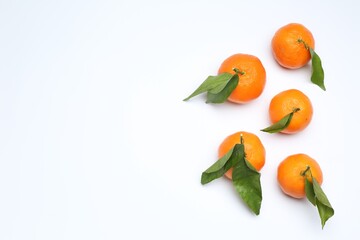 Ripe tangerines and green leaves on white background, flat lay. Space for text