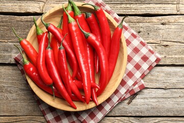 Ripe red chili peppers on wooden table, top view