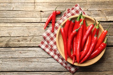 Ripe red chili peppers on wooden table, flat lay. Space for text
