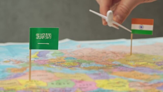 Toy airplane flying from India to Saudi Arabia across detailed world map, symbol labor migration, Umrah travel, budget airlines and strong air connection between India and Gulf region.