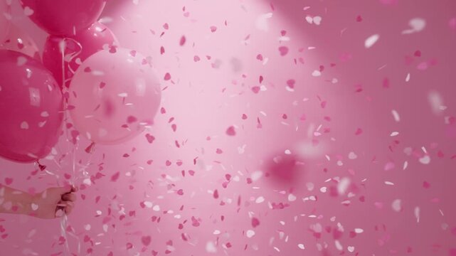 Hand Holding Pink Balloons and Heart-shaped Confetti Scene