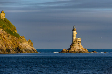 Illuminated lighthouse standing tall against a serene ocean backdrop at dusk