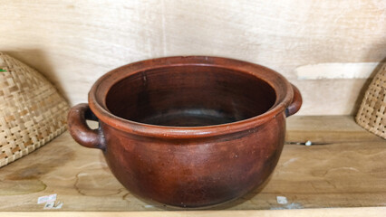 Traditional handmade clay teapot and cups displayed on a wooden shelf, showcasing rustic pottery...