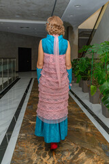 Elegant woman wearing a colorful dress walks through a stylish indoor space