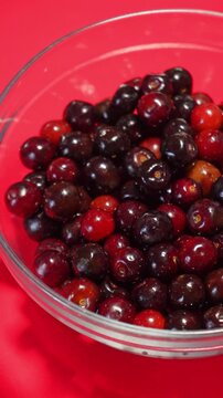 Fresh ripe cherries in a glass bowl on vibrant red background