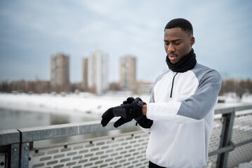 Young man adjusting fitness tracker on wrist during winter run