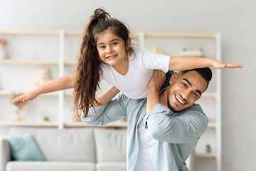 Happy arab father and daughter having fun together at home, middle-eastern young man dad playing...