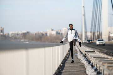 Black man stretching on bridge before winter run