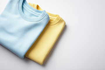 Folded blue and yellow cotton t-shirts on white background with copy space