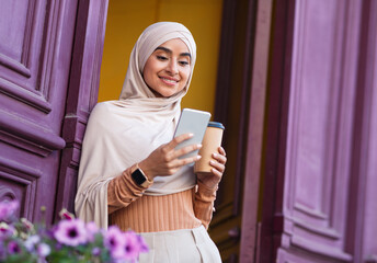 Glad attractive millennial middle eastern woman in hijab chatting on phone and enjoying favorite...