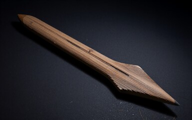 Wooden arrow lies on dark surface, showcasing craftsmanship and natural grain patterns.