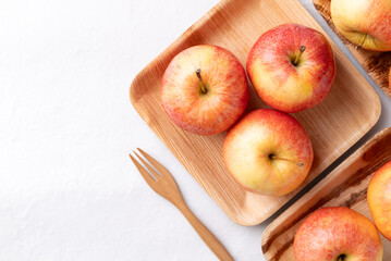 Red apple fruit (Gala apple) in natural plate with wooden fork on white background, Top view