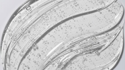 Abstract macro shot of thick, clear cosmetic gel spread on a white background, highlighting wavy texture and trapped air bubbles, conveying purity and hydration.