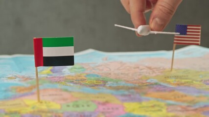 Toy airplane flying from United States to United Arab Emirates above colorful world map, symbol business conferences, luxury vacations, stopover tourism and premium air travel.