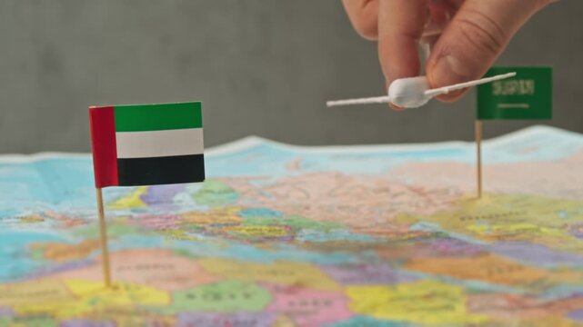 Toy airplane flying from Saudi Arabia to United Arab Emirates over political world map, symbol weekend getaways, business shuttles, family visits and short haul regional flights.
