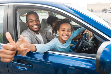 Family Approving New Car. Happy African American Father And Daughter Gesturing Thumbs Up Sitting In Automobile, Smiling To Camera. Road Trip, Transportation. We Like Our Auto. Selective Focus