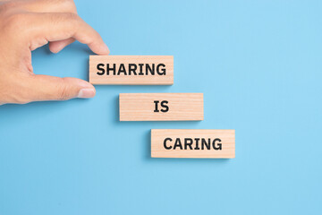 Sharing is caring symbol. Wooden blocks with words 'Sharing is caring' on beautiful white background. Businessman hand. Business, sharing is caring concept. Copy space.