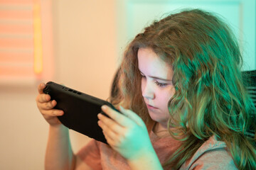 Gaming technology device. Gamer focused on the screen. Kid player focused on a gaming display. Teenager using game controller at home. Child using game controller playing video console game.