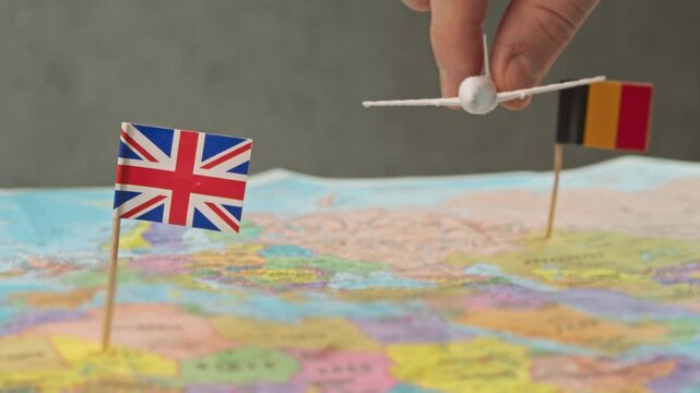 Toy airplane flying from United Kingdom to Belgium above political world map, symbol EU business travel, weekend tourism, quick flights and international air connection.