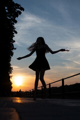 Silhouette of a young woman dancing at sunset outdoors. Graceful girl enjoying freedom and carefree...