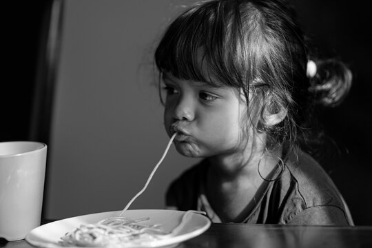 Kid funny eating with spaghetti. Kid slurping noodles. Child eat pasta meal. Portrait of kid eating spaghetti. Cute child eating spaghetti at home. Messy kids face. Toddler girl enjoying pasta.