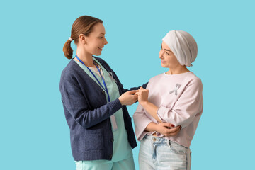 Fototapeta premium Young woman after chemotherapy with nurse holding hands on blue background. Brain cancer concept