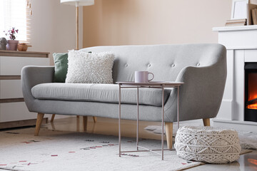Naklejka premium Interior of living room with grey sofa, table and pouf