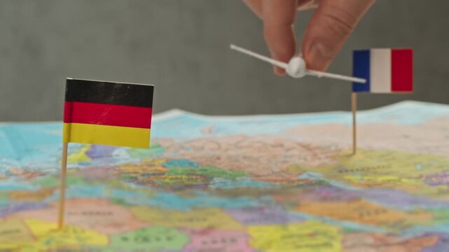 Toy airplane flying from France to Germany across detailed world map, symbol city breaks, trade fairs, business travel and busy cross border air connection.