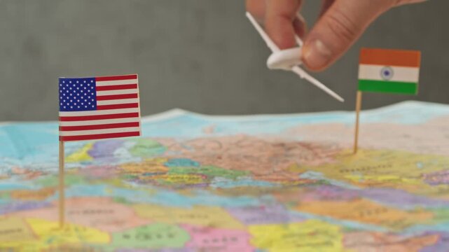 Toy airplane flying from India to United States above world map, symbol student migration, IT business travel, family visits and growing intercontinental tourism.
