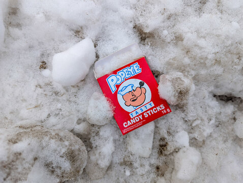 Canada, Quebec, 23 November 2025 : Popeye candy sticks box discarded on the dirty snowy ground