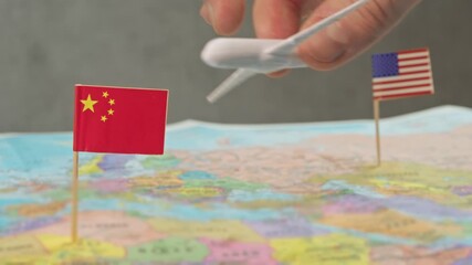 Toy airplane near China and United States flags above colorful world map, symbol long haul routes, cargo traffic, tourism charters and strategic expansion in US air travel market.