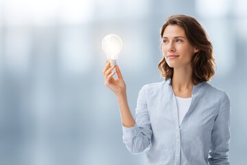Professional female business executive holding a glowing lightbulb symbolizing innovation and new ideas.