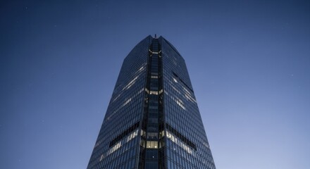 Modern glass skyscraper soars toward a deep blue twilight sky with visible stars